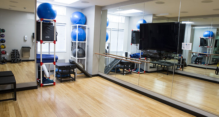 Fitness studio with wood floors, mirrors, and workout equipment