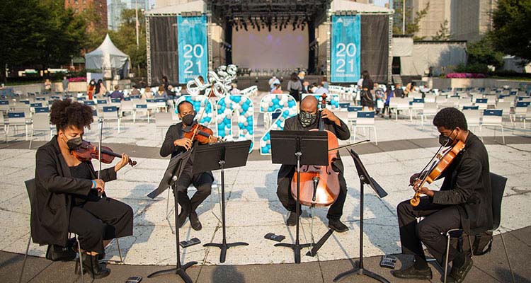 Four person string orchestra plays music in Damrosch Park.