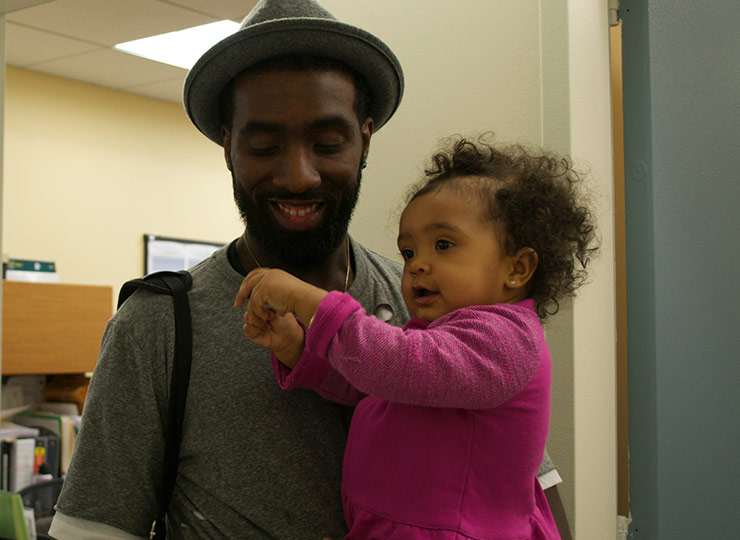 Father holds smiling daughter-patient in pediatric office